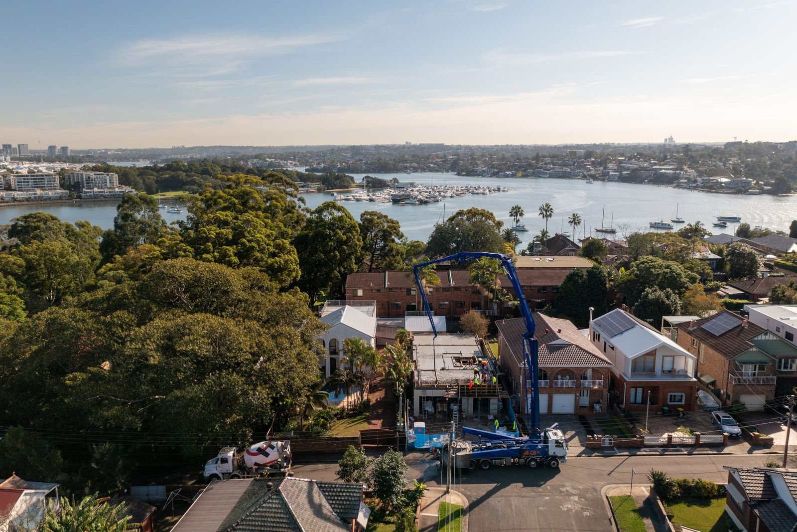 Wide view of the street in late sun, the pump beside the site and the Parramatta River and city towers behind