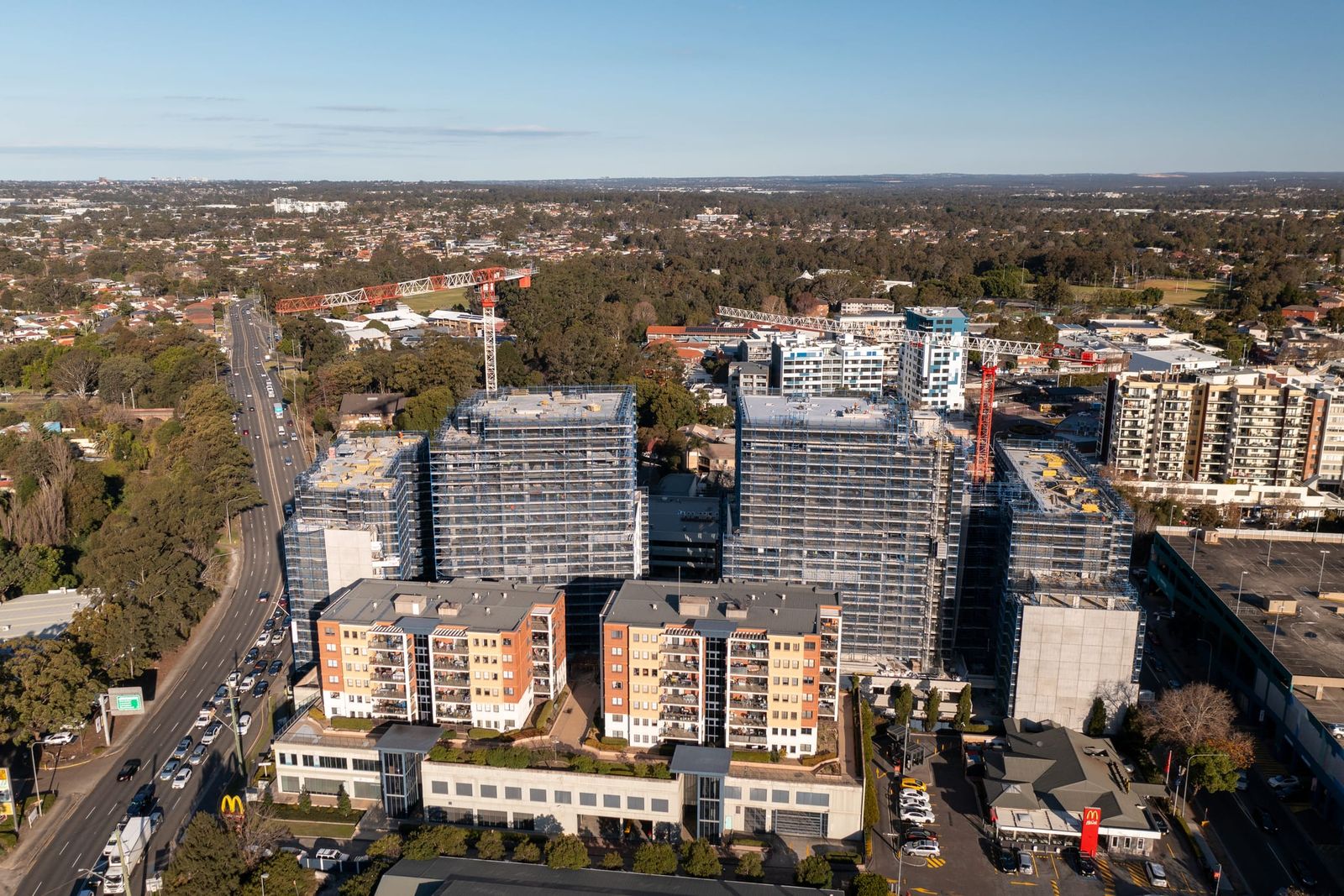 Front-on view of the towers behind a row of low-rise apartments on the main road