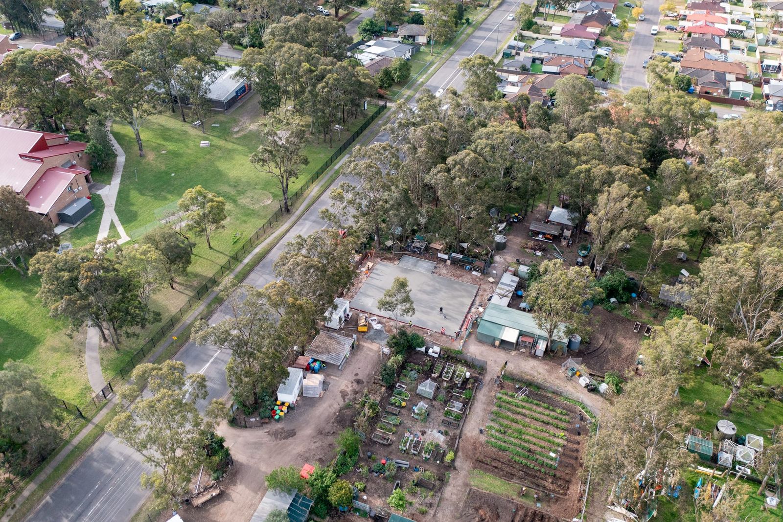 Wide view over the suburb, the slab in its clearing between the park, the road and neighbouring houses