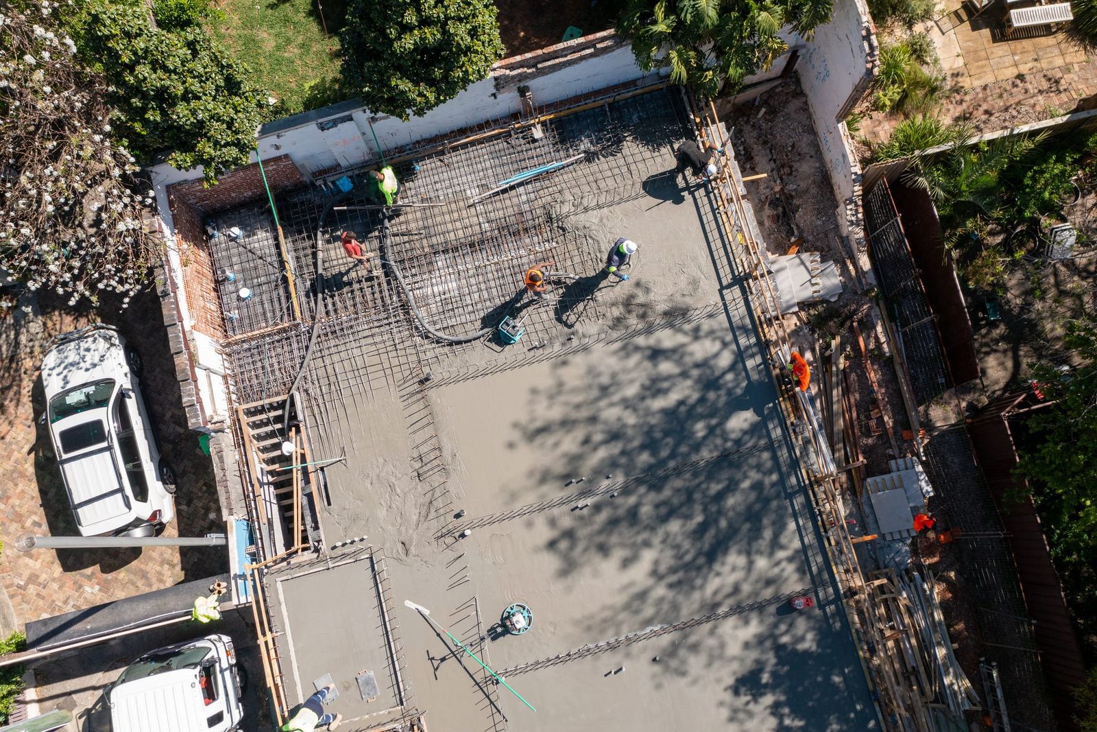 Top-down view of the pour, crew spreading concrete over the reinforcement with the pump hose across the deck
