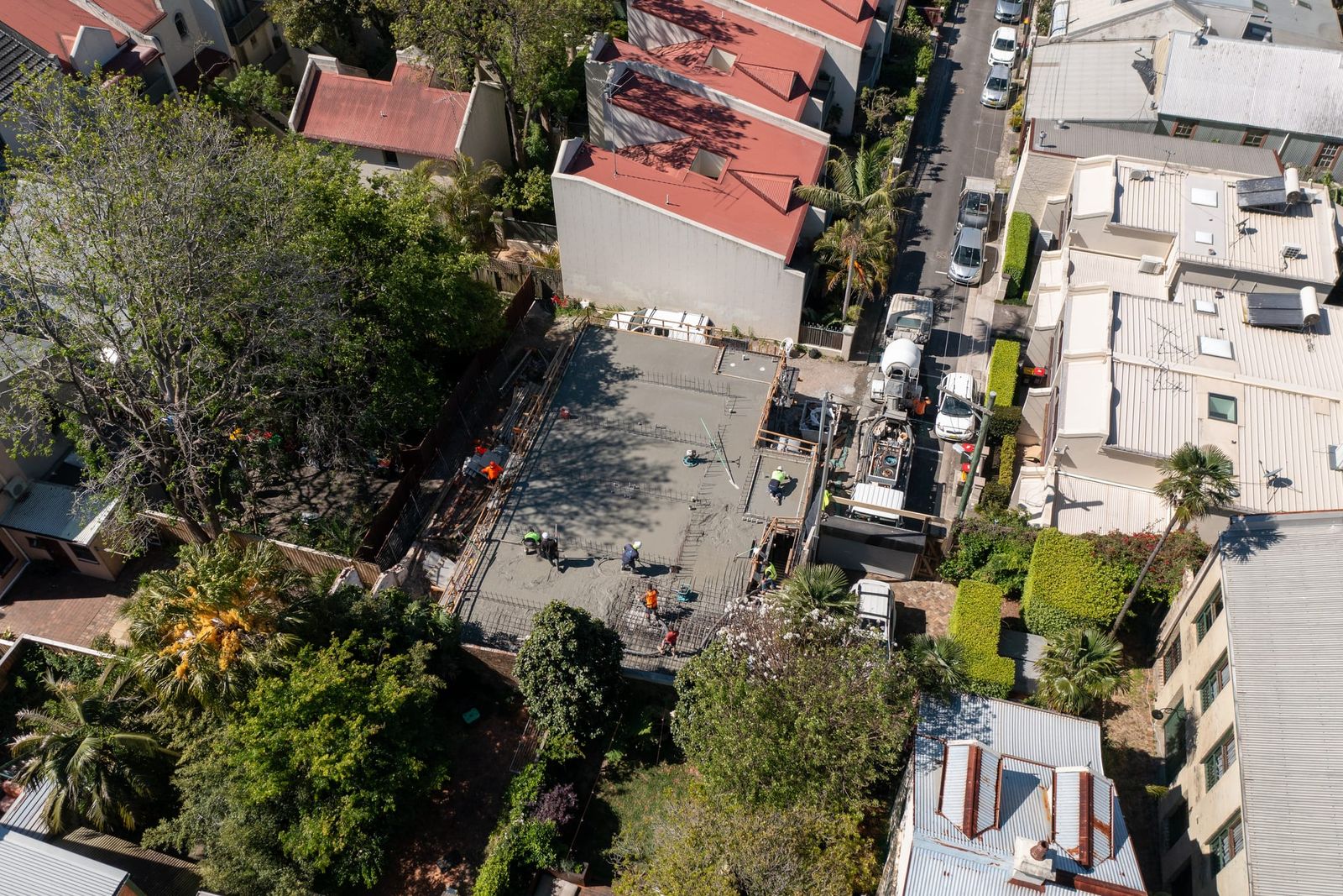 Higher view of the site behind the terraces, trucks lined up in the lane for the pour