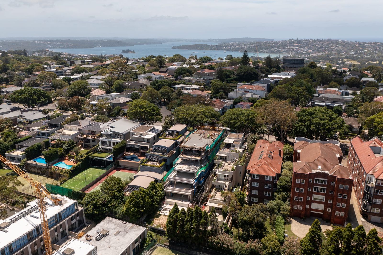 Wide view over the eastern suburbs to the harbour, the site among houses and red-brick flats in the middle distance