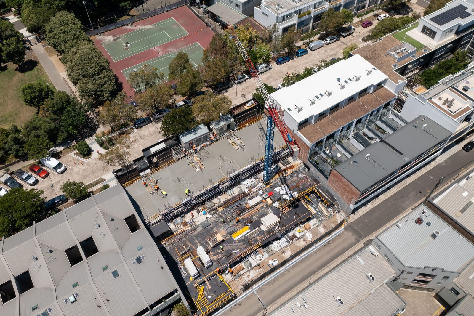 High view of the site beside a street of townhouses and a tennis court, formwork and materials across the deck