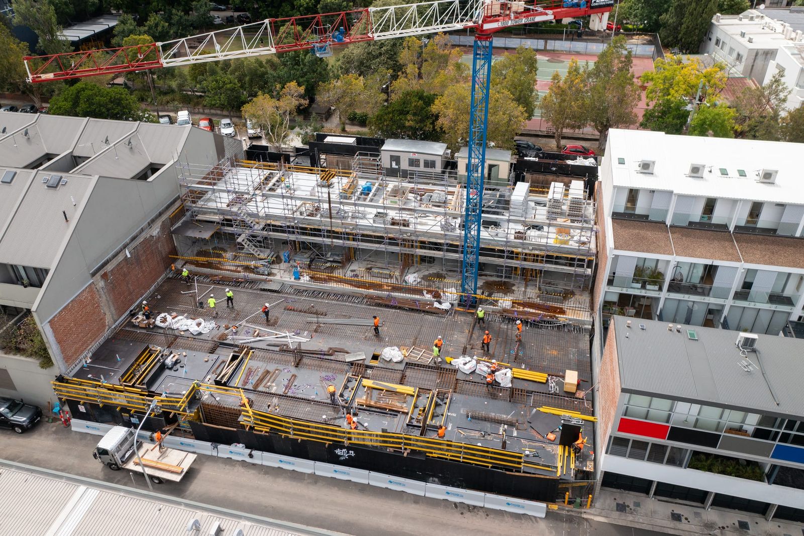 Crew spread across the formwork deck, the crane jib overhead and scaffold stair towers at the rear of the site