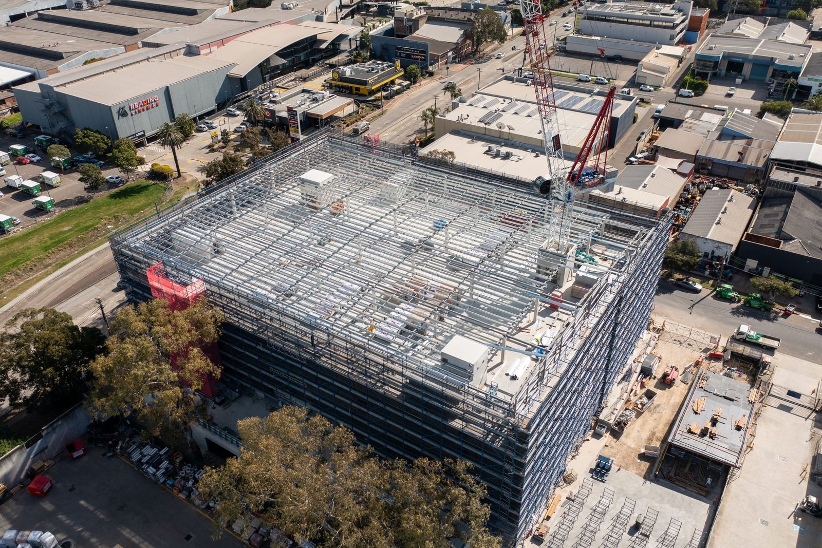 High view over the top of the scaffolded building, the industrial estate and a warehouse car park alongside