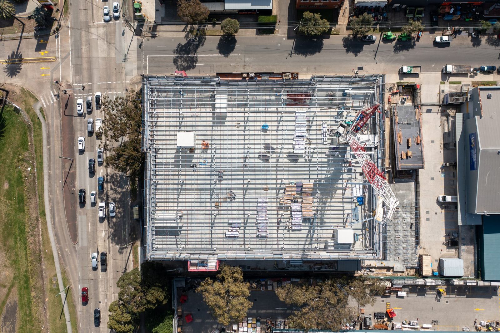 Top-down view of the roof and scaffold perimeter beside a multi-lane road and intersection