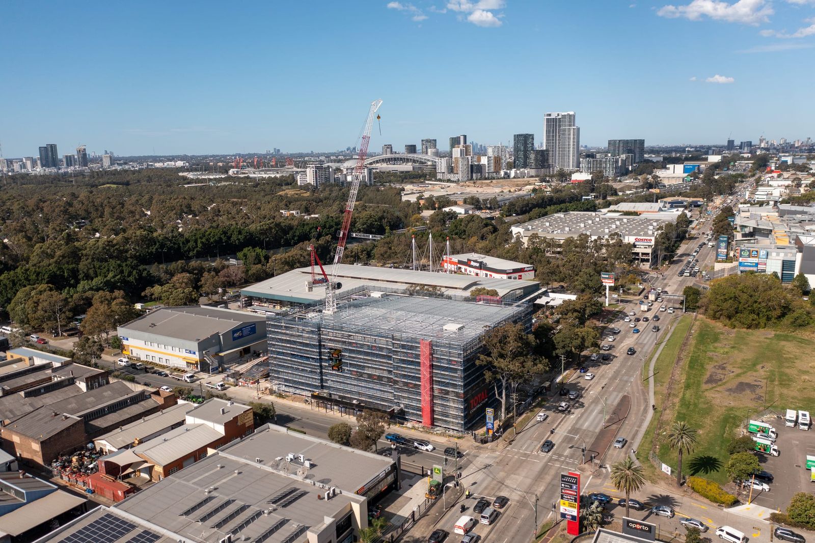 Wide view of the site among industrial buildings, the Olympic Park towers and stadium in the distance