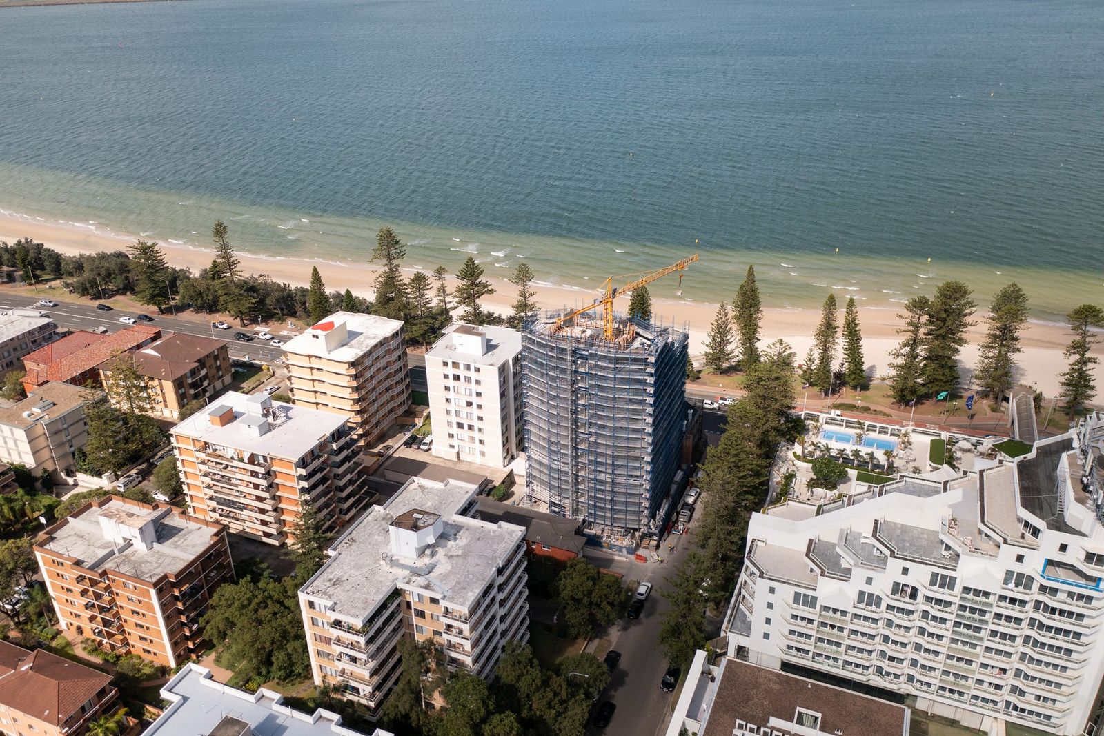 Front-on view of the scaffolded tower facing Botany Bay, apartment blocks on either side