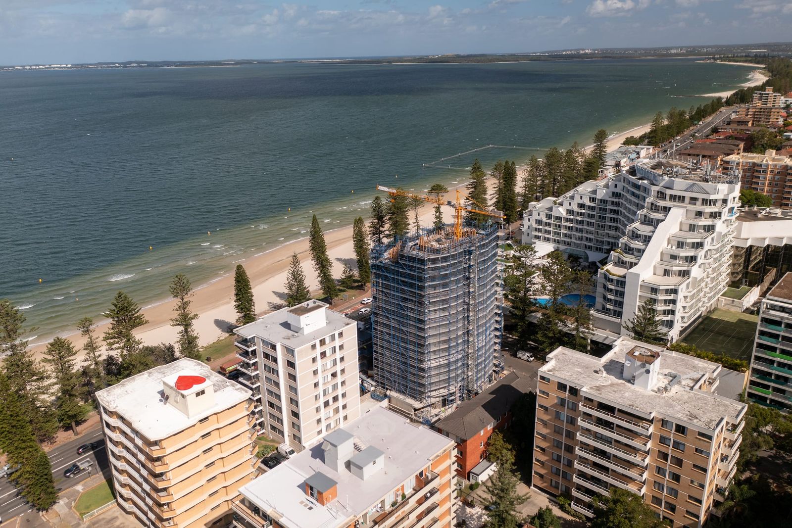 The tower rising above neighbouring apartment blocks, the bay and the curve of the beach beyond