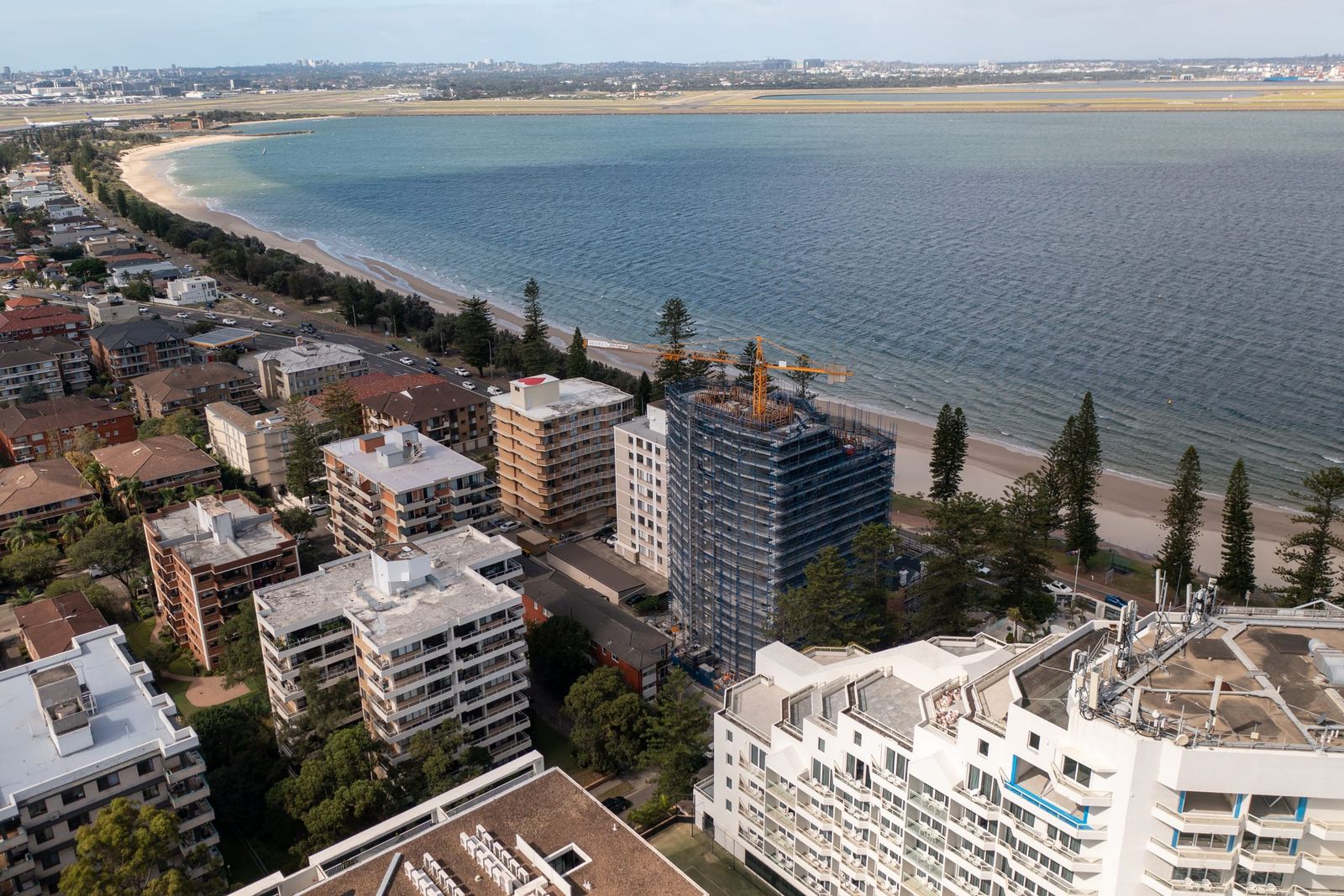 Long view along the foreshore towards the airport, the scaffolded tower standing out among the beachfront buildings