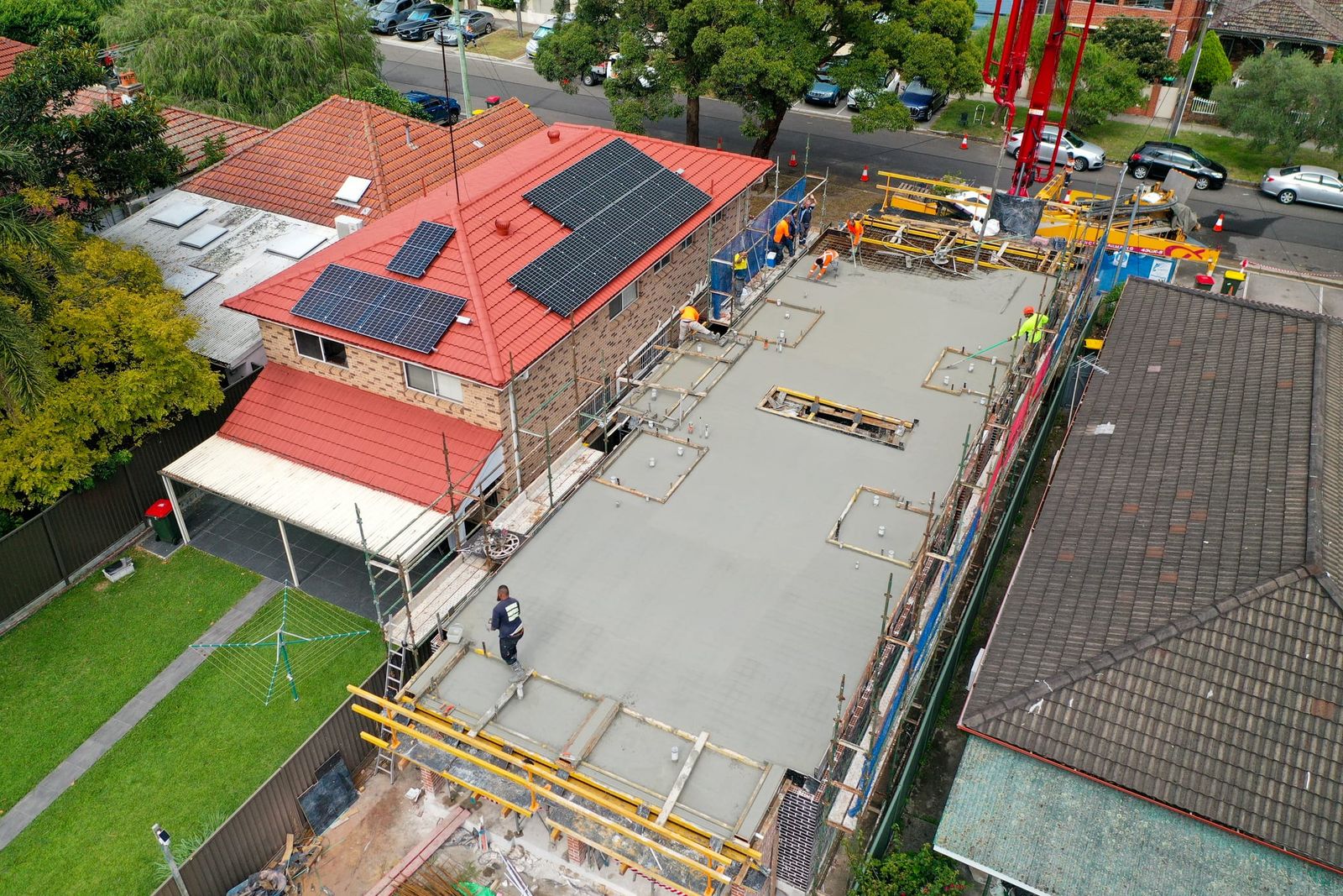 Close aerial of the suspended slab with yellow formwork props below and a worker on the deck