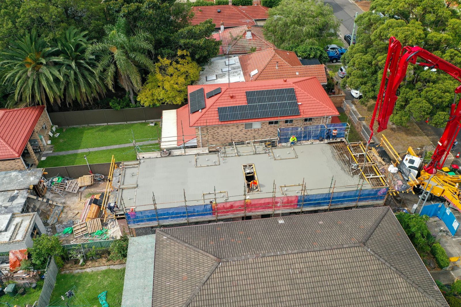 Side-on view of the deck behind blue edge protection, the red pump boom beside the site