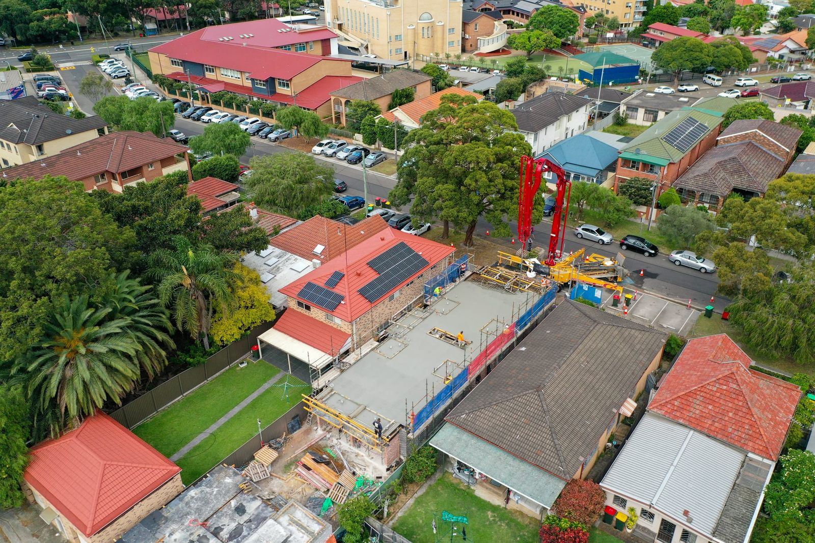 Higher view of the slab between red-tiled houses, the pump truck on the street and a large sandstone building behind