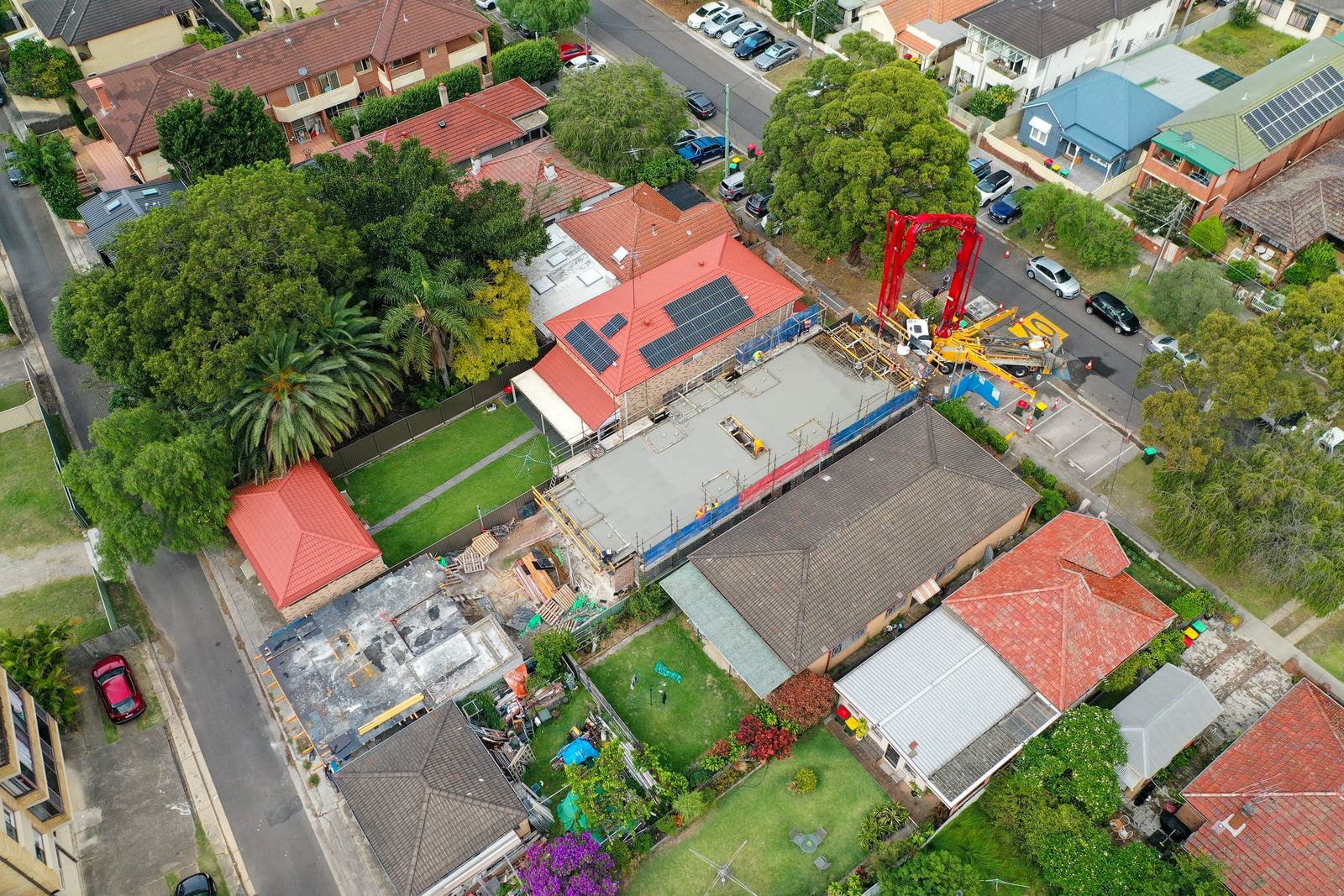 Angled view over the site and neighbouring yards, the pump on the street and trees along the footpath