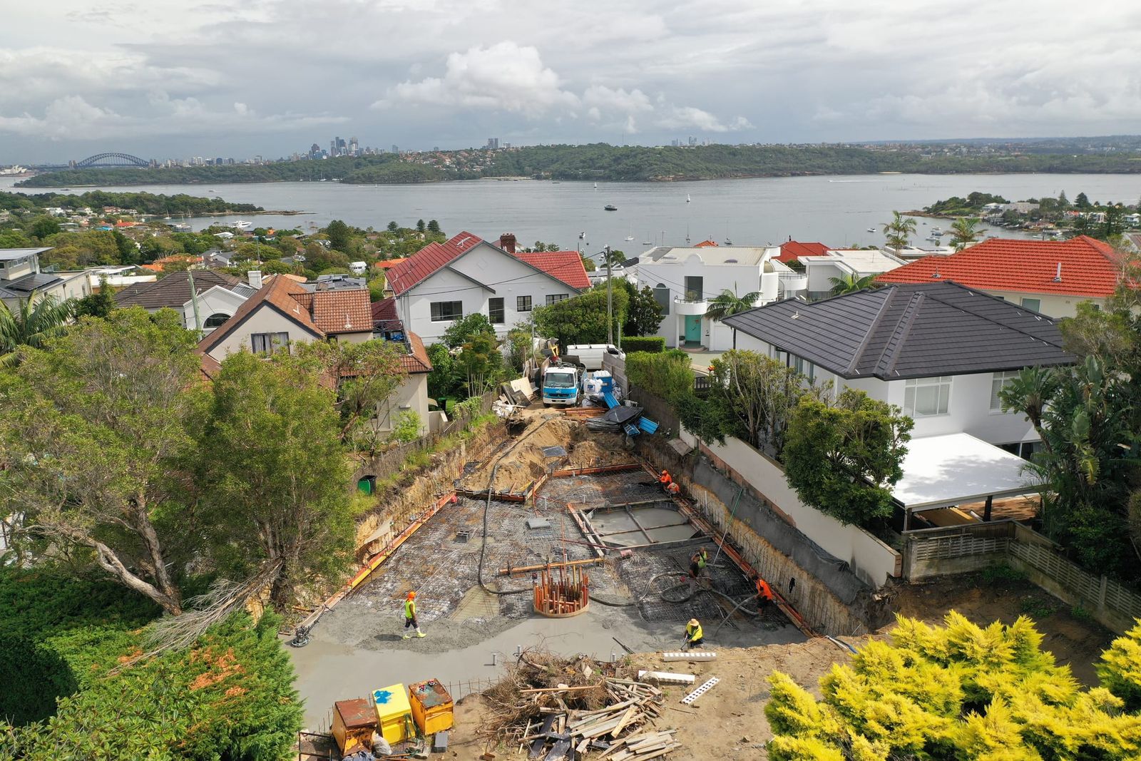 The excavation and pump line from above the street, the harbour and city skyline in the distance