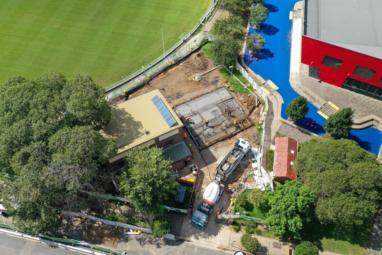 High view of the site among trees, the brick building and pump truck beside the oval fence