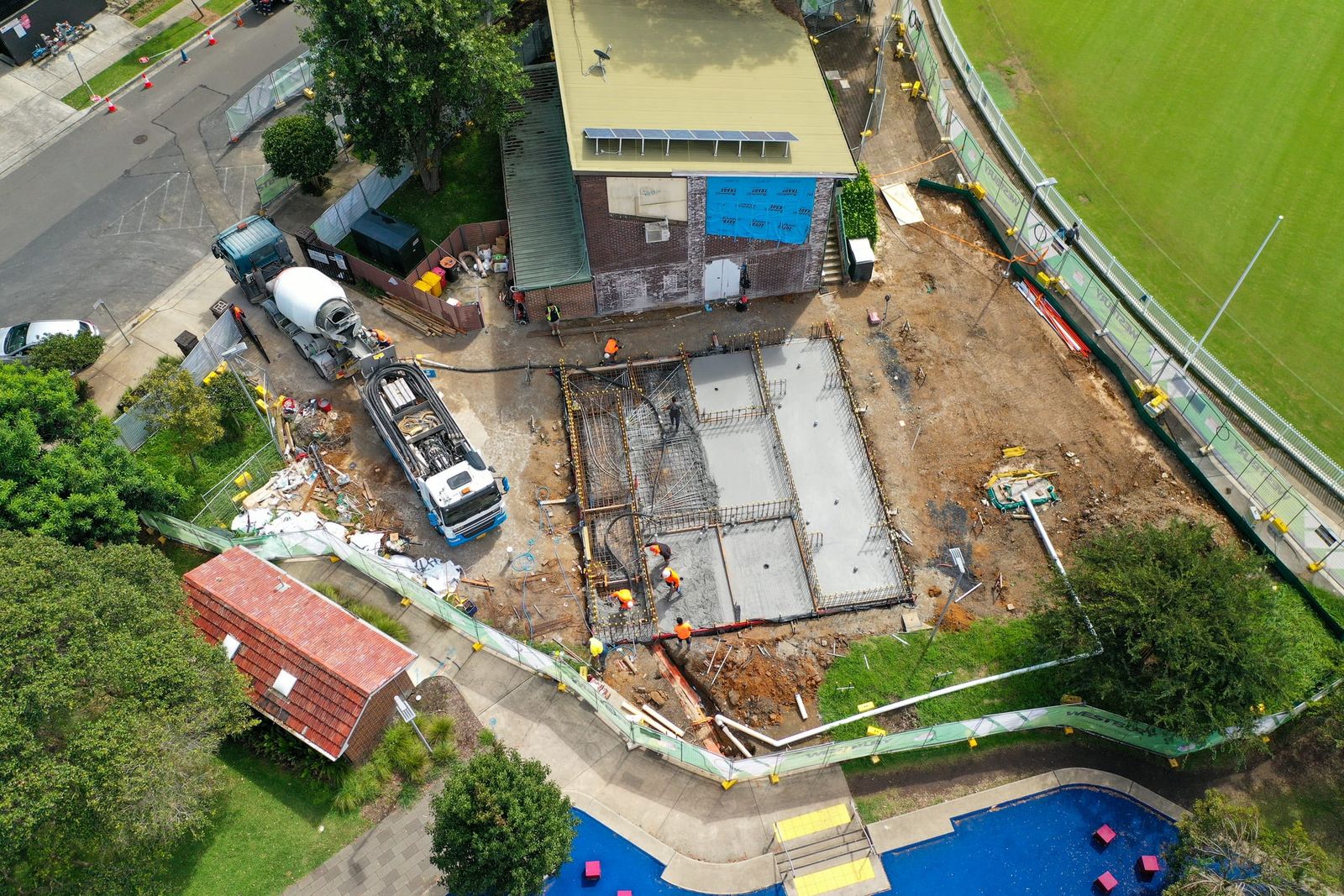 Top-down view of the slab and footings, the pump truck and agitator on the path beside the site