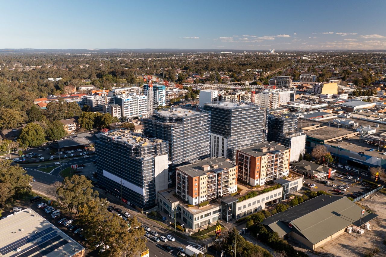 Aerial view of the Fairfield town centre in late sun, scaffolded residential towers rising beside lower apartment blocks and shops