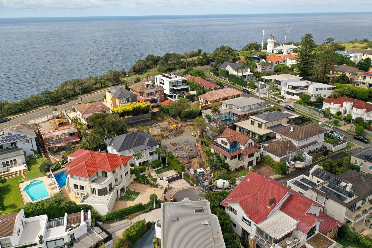 Vaucluse from above, the excavated site among houses and pools, the ocean and Macquarie Lighthouse on the clifftop