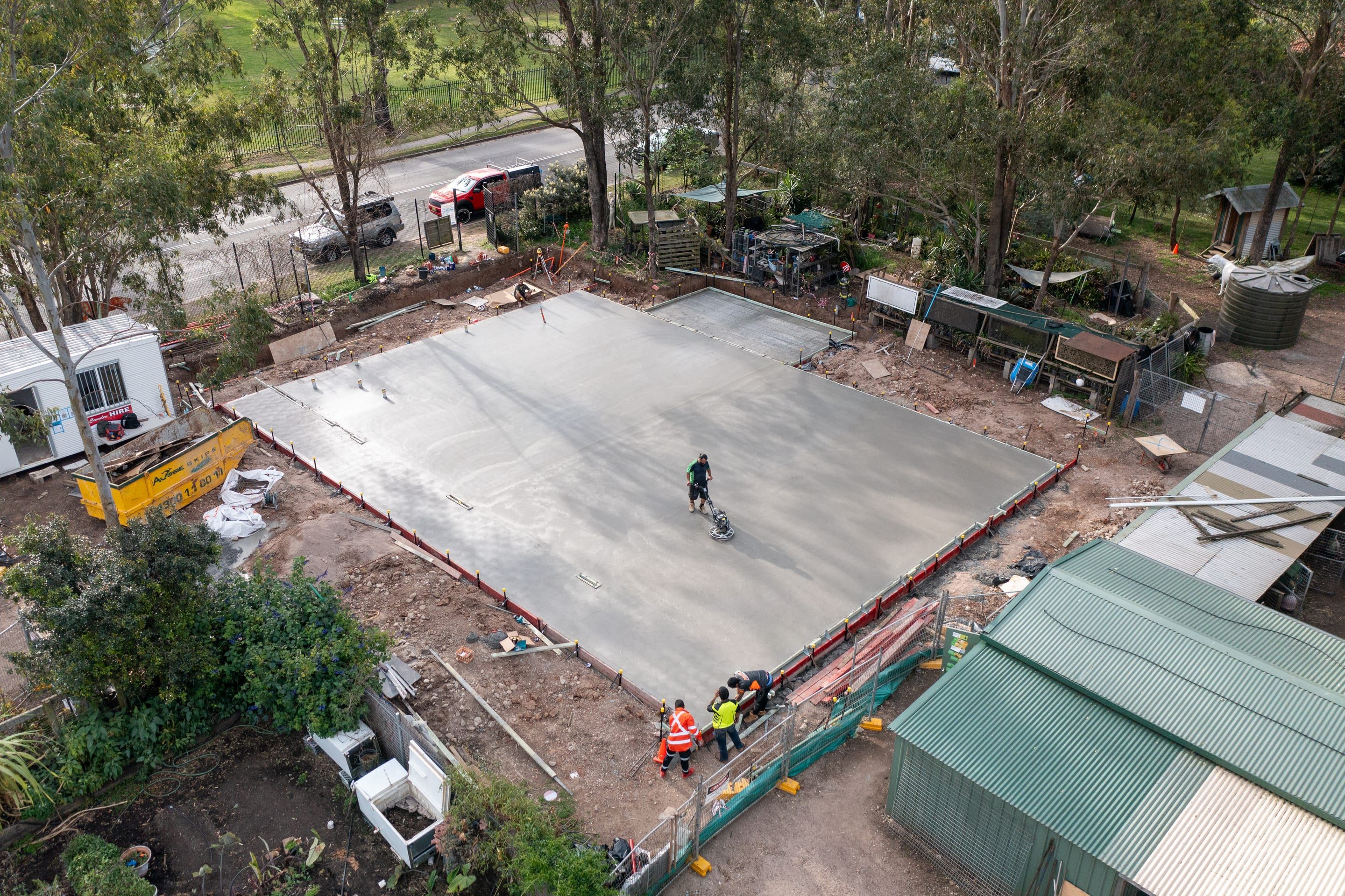 Closer view of the slab being finished, crew at the edge formwork and a site office beside the pour