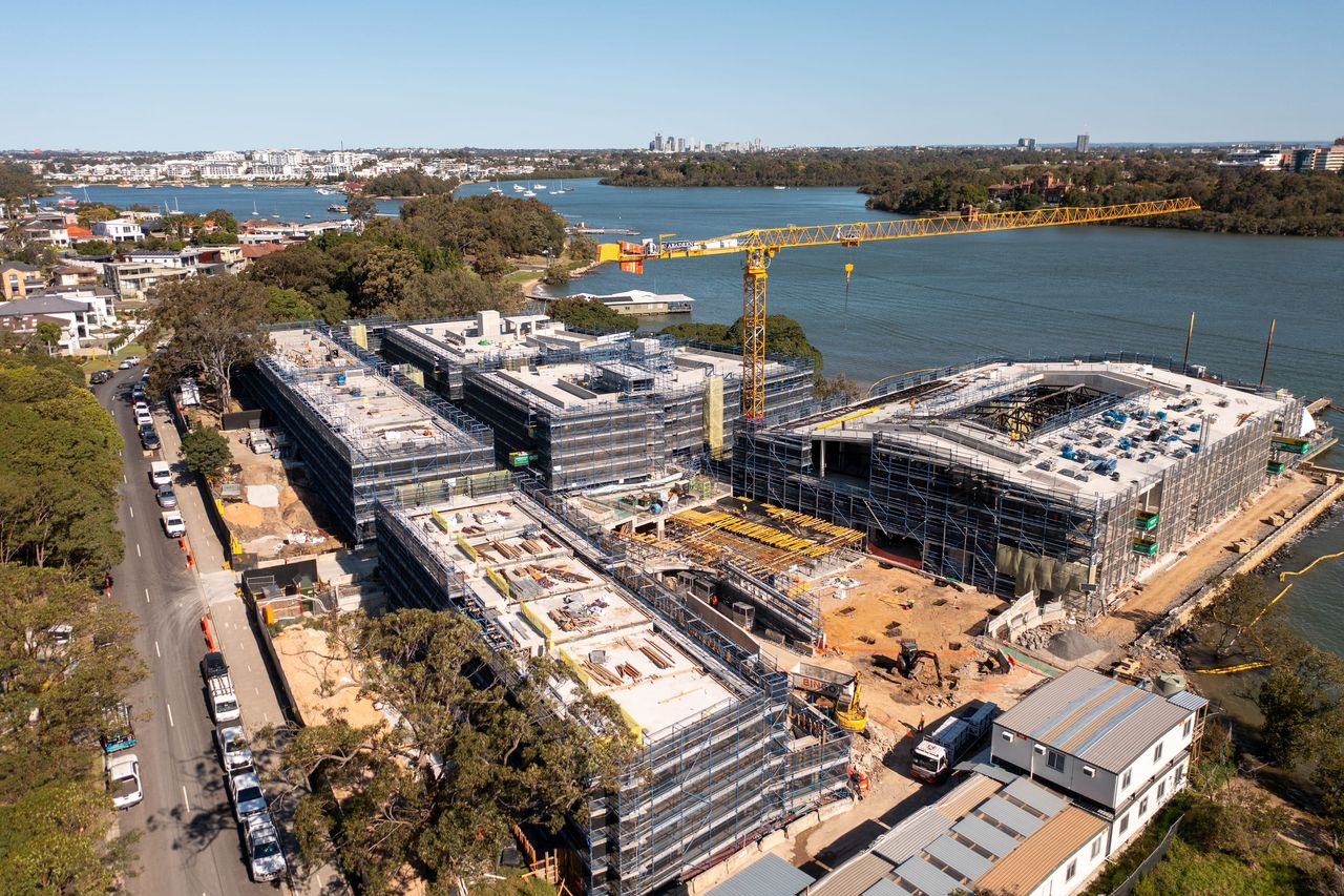 Aerial view of the Putney development on the Parramatta River, several scaffolded buildings around a yellow tower crane