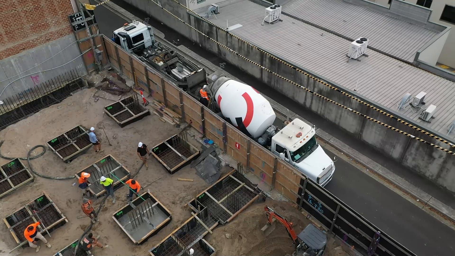 Frame from drone footage of an inner-city podium slab pour, concrete truck at the hoarding